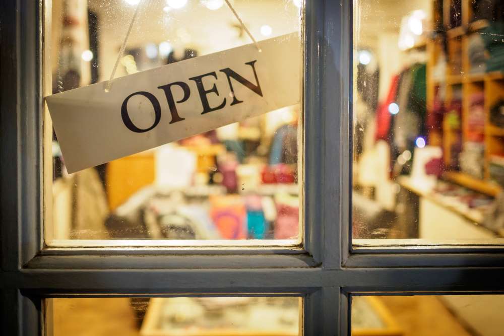 Open sign hanging on the door of a small private business selling clothes.