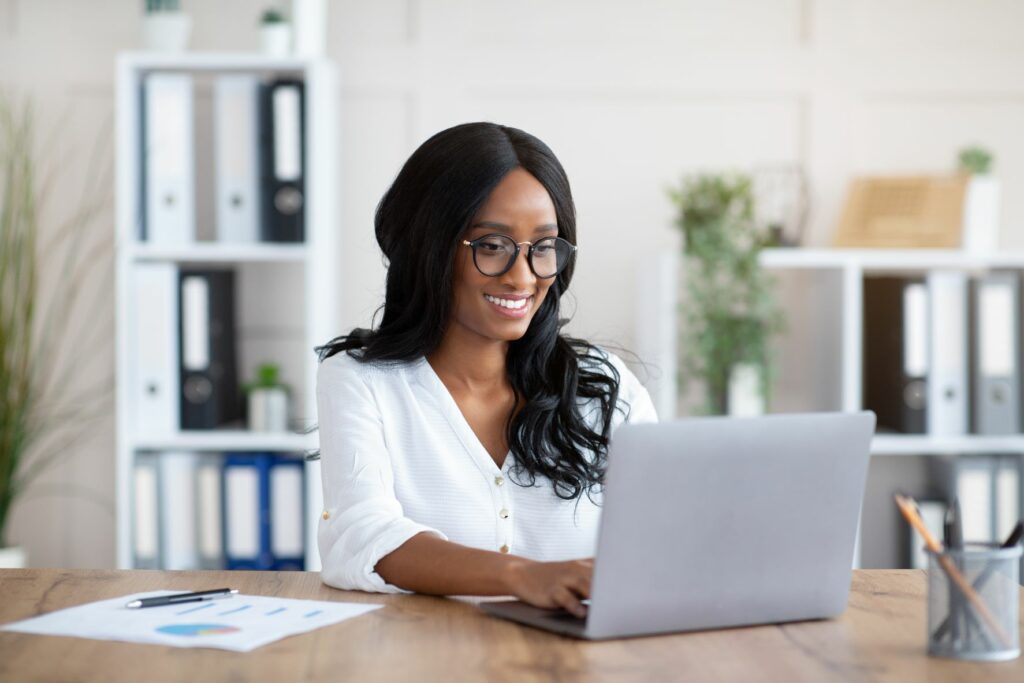 Woman smiling on a laptop completing financial documents 