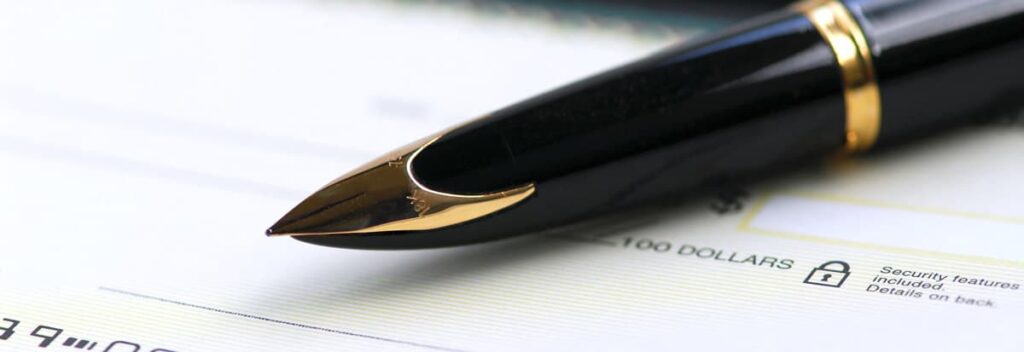 pen laying on top of a checkbook to indicate the real-time access to your retirement funds with a Checkbook IRA.