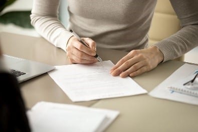 Woman filling out paper work to take out a loan from a Solo 401(k)