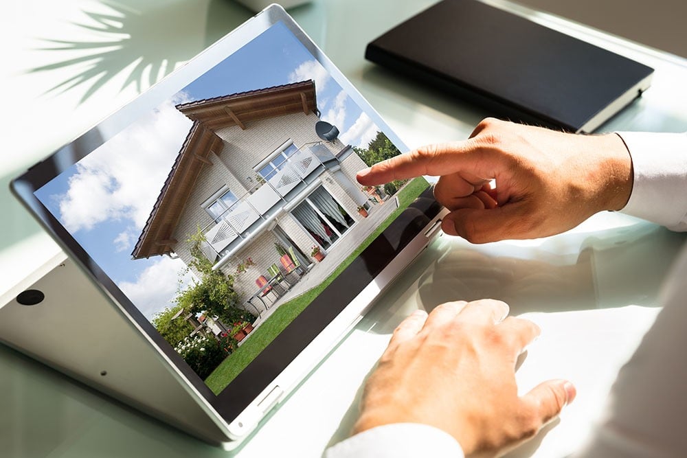 Real estate investor pointing a a beautiful property on a tablet, as they are looking to buy real estate with their SDIRA.