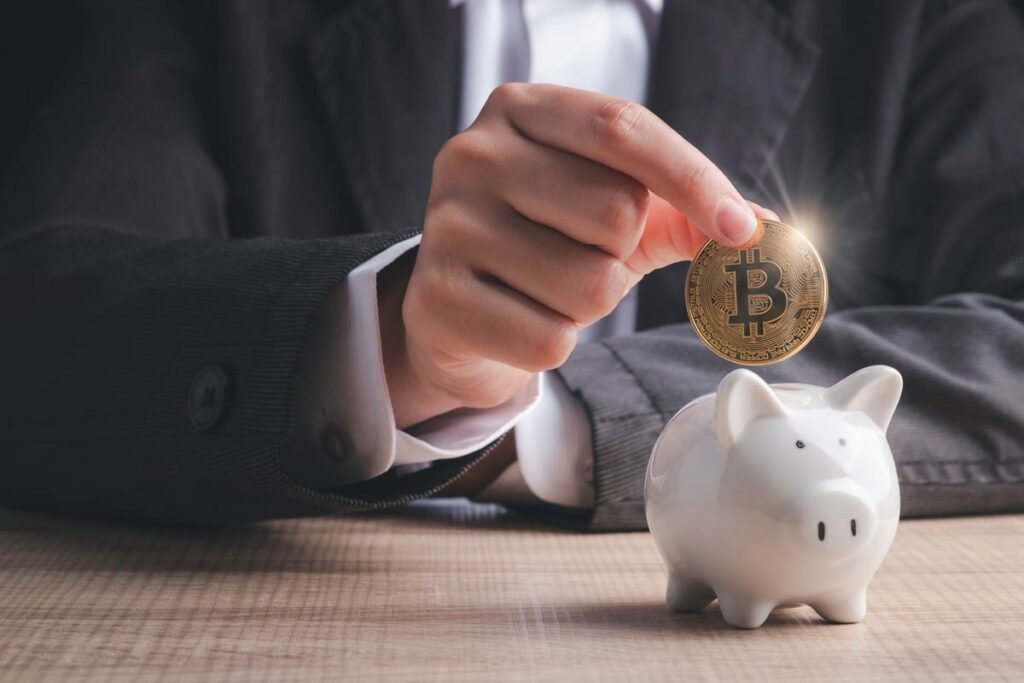 Cryptocurrency investor placing Bitcoin into his piggy bank to signify investing in cryptocurrency with a Self-Directed Crypto IRA LLC.