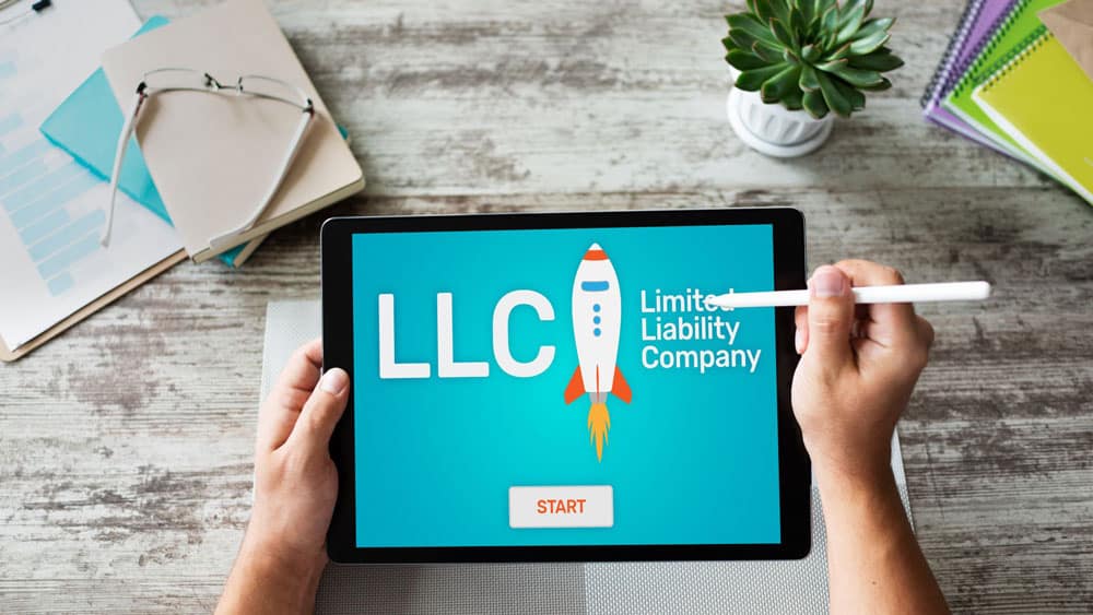 Investor on a tablet that says "LLC" to indicate that you can invest in a Limited Liability Company with a Self-Directed IRA