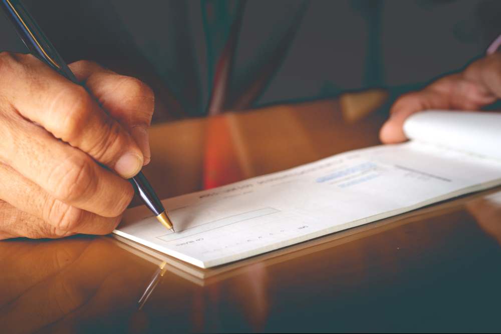 Closeup of businessman hand writing and signing checkbook for his ira